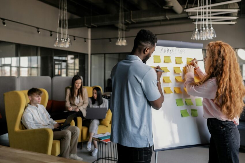 Team collaborating in a modern office, planning strategy on a whiteboard, young adults working together.