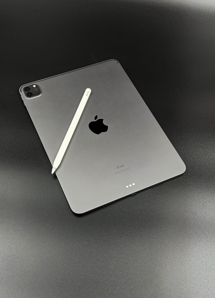 Apple iPad with Apple Pencil on a sleek black surface, showcasing minimalist design.