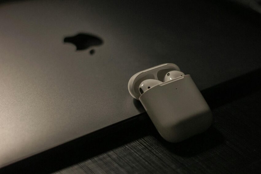 Sleek wireless earbuds in a case resting on a laptop surface, showcasing modern technology.