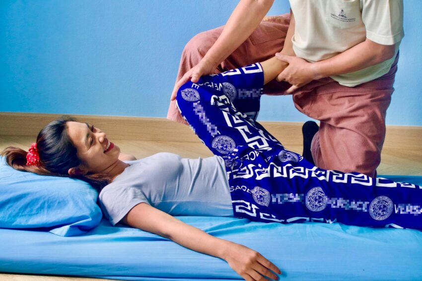 Young woman enjoys a relaxing leg stretch therapy session indoors with professional care.