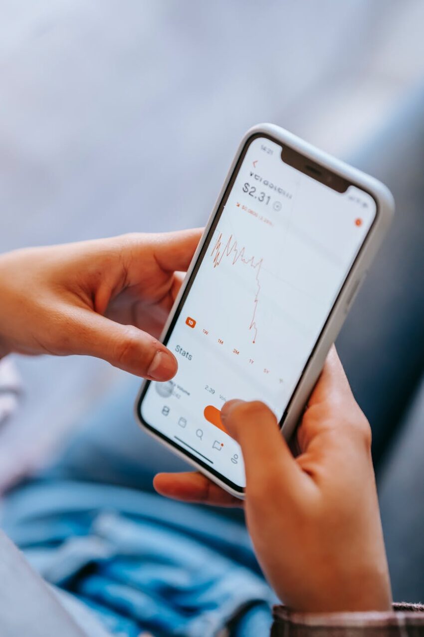 Close-up of hands holding a smartphone displaying a financial app with stock data.