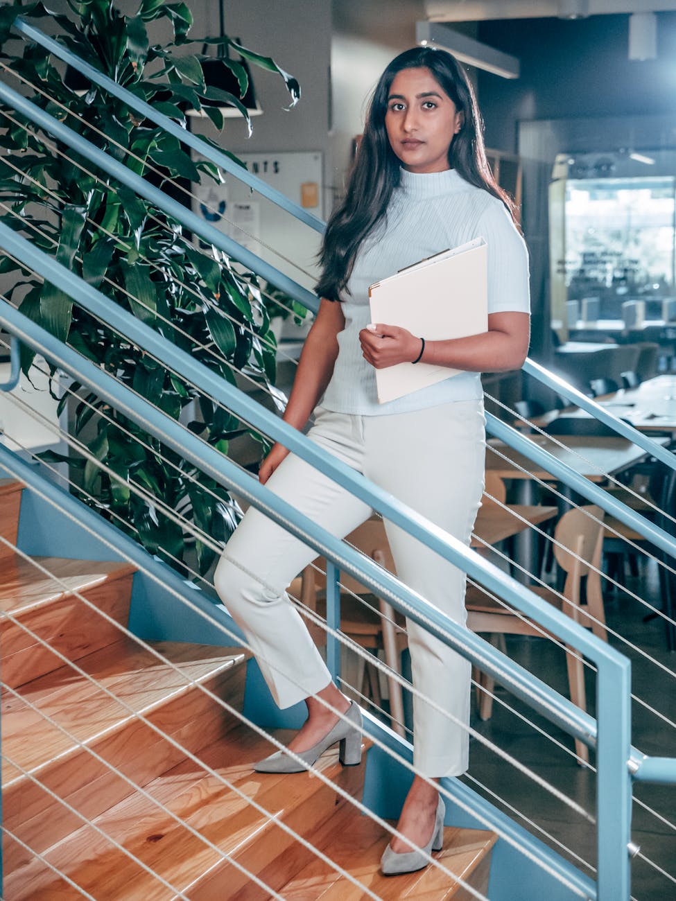 Confident businesswoman holding documents on a modern office staircase.