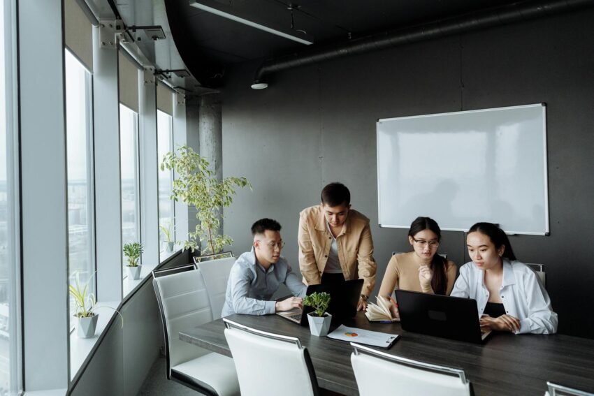 Diverse group of professionals collaborating around laptops in a modern office setting.