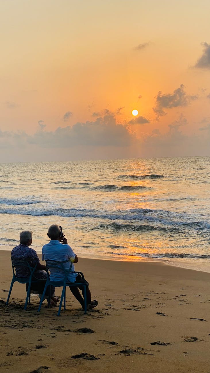 A serene moment of an elderly couple sitting on a beach, enjoying the sunrise.