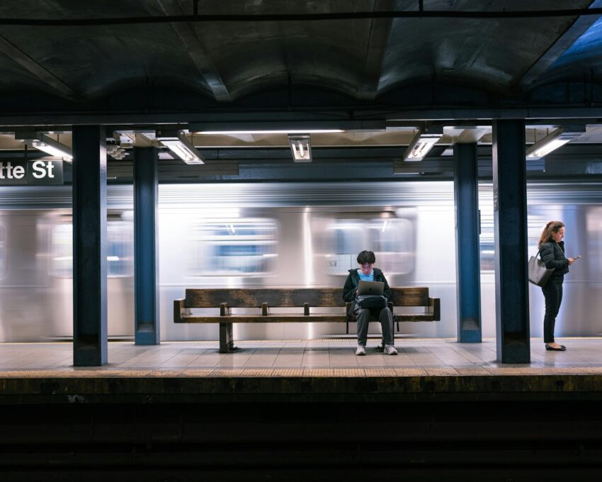 Dynamic scene of people waiting at a subway station in New York City with a blurred train passing.