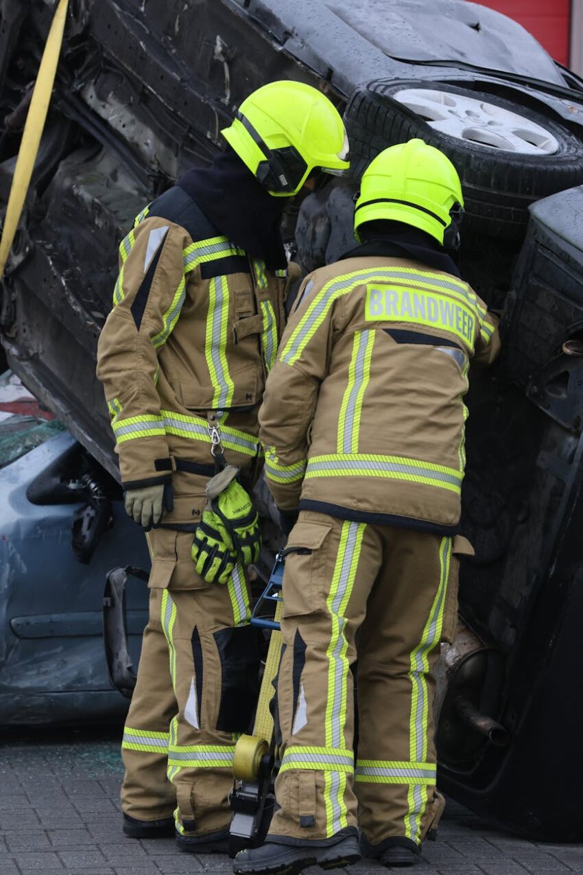Firefighters in full gear inspect an overturned vehicle after an accident.