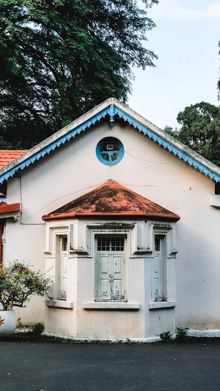 Vintage colonial house facade with red roof and blue trim in Bengaluru, India.