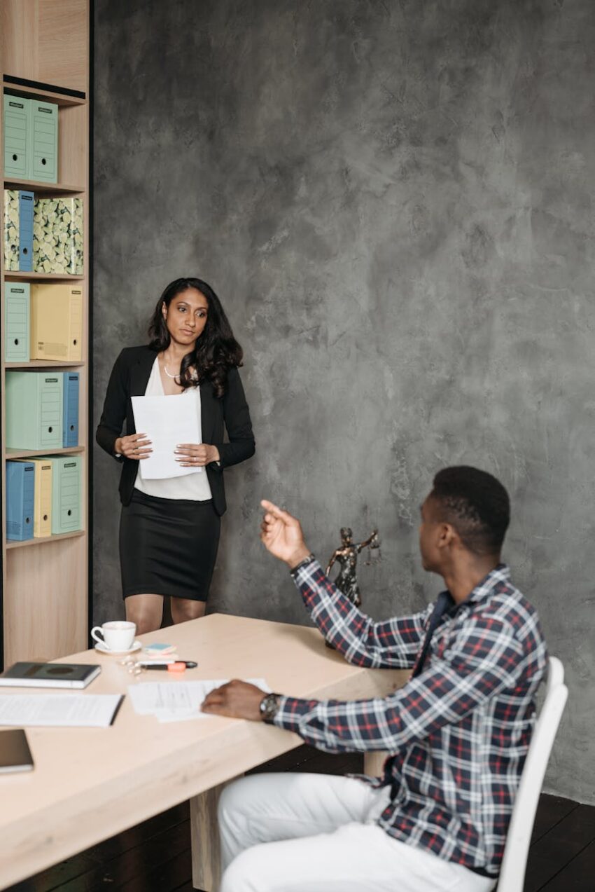 Business professionals communicating in a modern office setting, discussing legal documents.