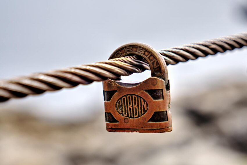 Close-up of a Corbin padlock on a cable, showcasing a rustic and textured look.