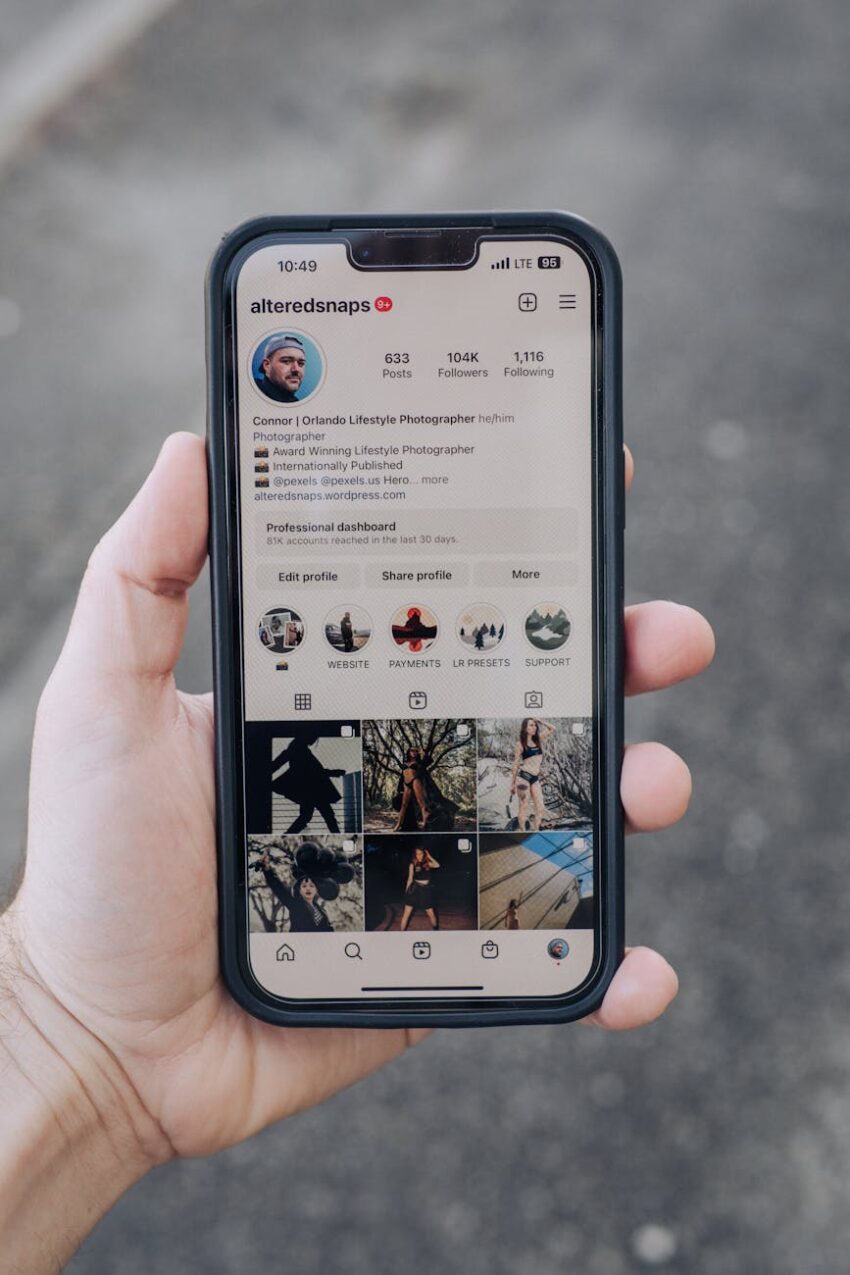 Close-up of a hand holding a smartphone showing a social media profile outdoors.
