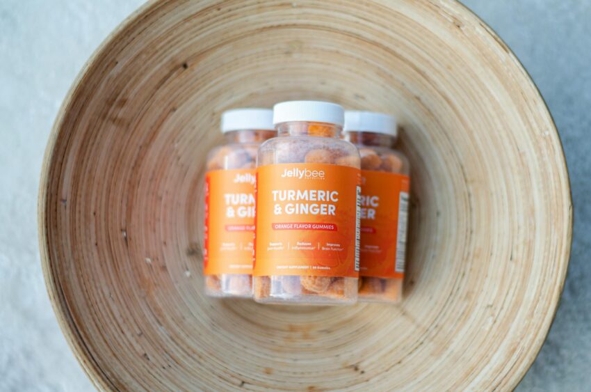 Close-up of Jellybee Turmeric & Ginger orange flavor gummies in a wooden bowl.