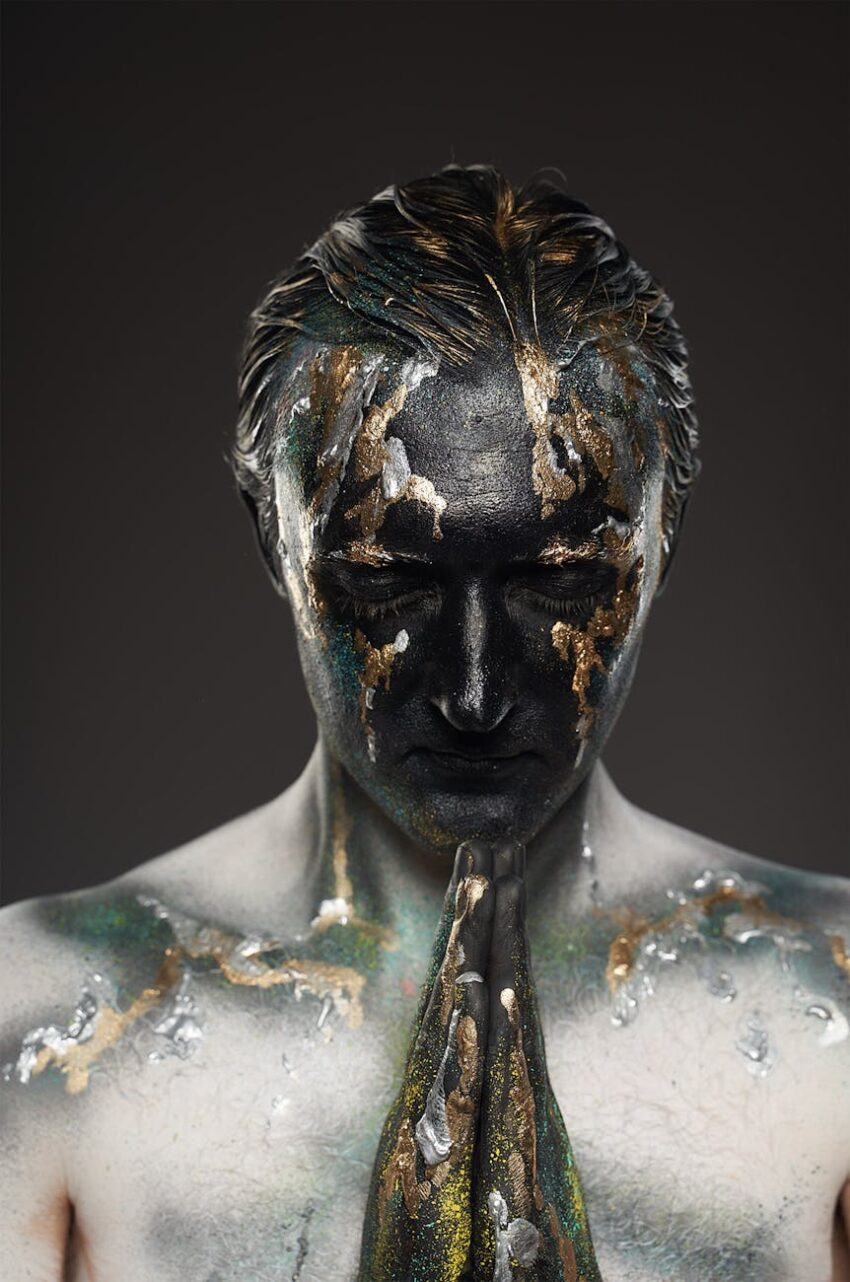 A dramatic artistic portrayal of a painted figure in a meditative pose, reflecting spirituality.