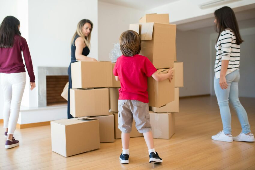 Family organizing and moving cardboard boxes in a bright room, creating a lively relocation scene.