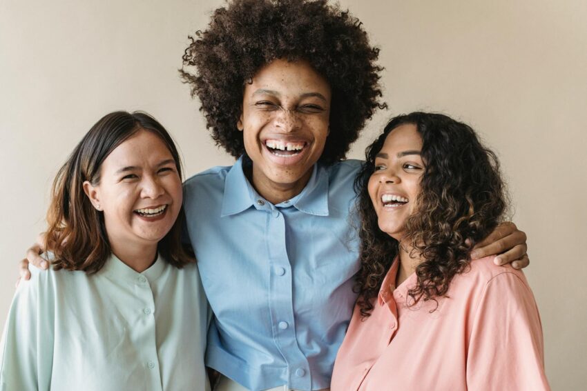 Three women of diverse backgrounds sharing a joyful moment, showcasing happiness and unity.