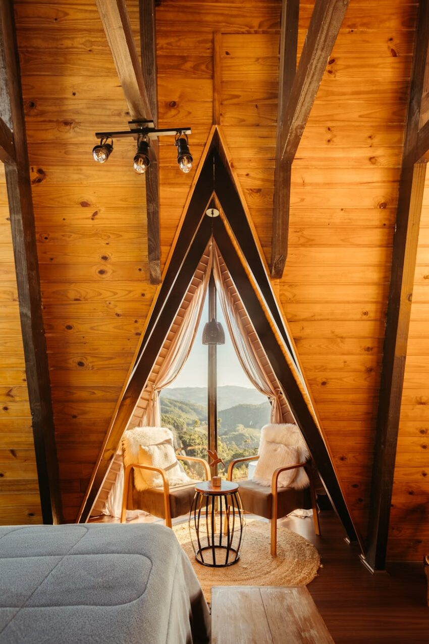 Warm A-frame cabin interior with window view of mountains.