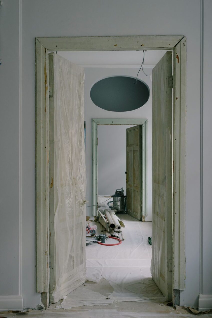 Contemporary house interior with open doors in cellophane and construction materials on floor in daytime